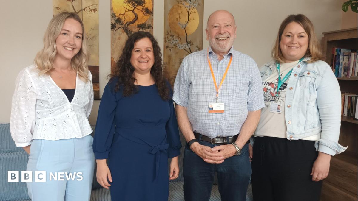 Four people stand in a room, three women and a man. They are Kayleigh Jones, Missing Link Service Manager for Oriana House, Sarah O’Leary, Missing Link CEO, Councillor Neil Hopkins, Swindon Borough Council, and Helen Brian, Albare Head of Mental Health. They are standing in a line smiling at the camera.