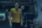 Two Starfleet officers on a starship bridge, one gripping the other's shoulder, both tense under blue lighting.