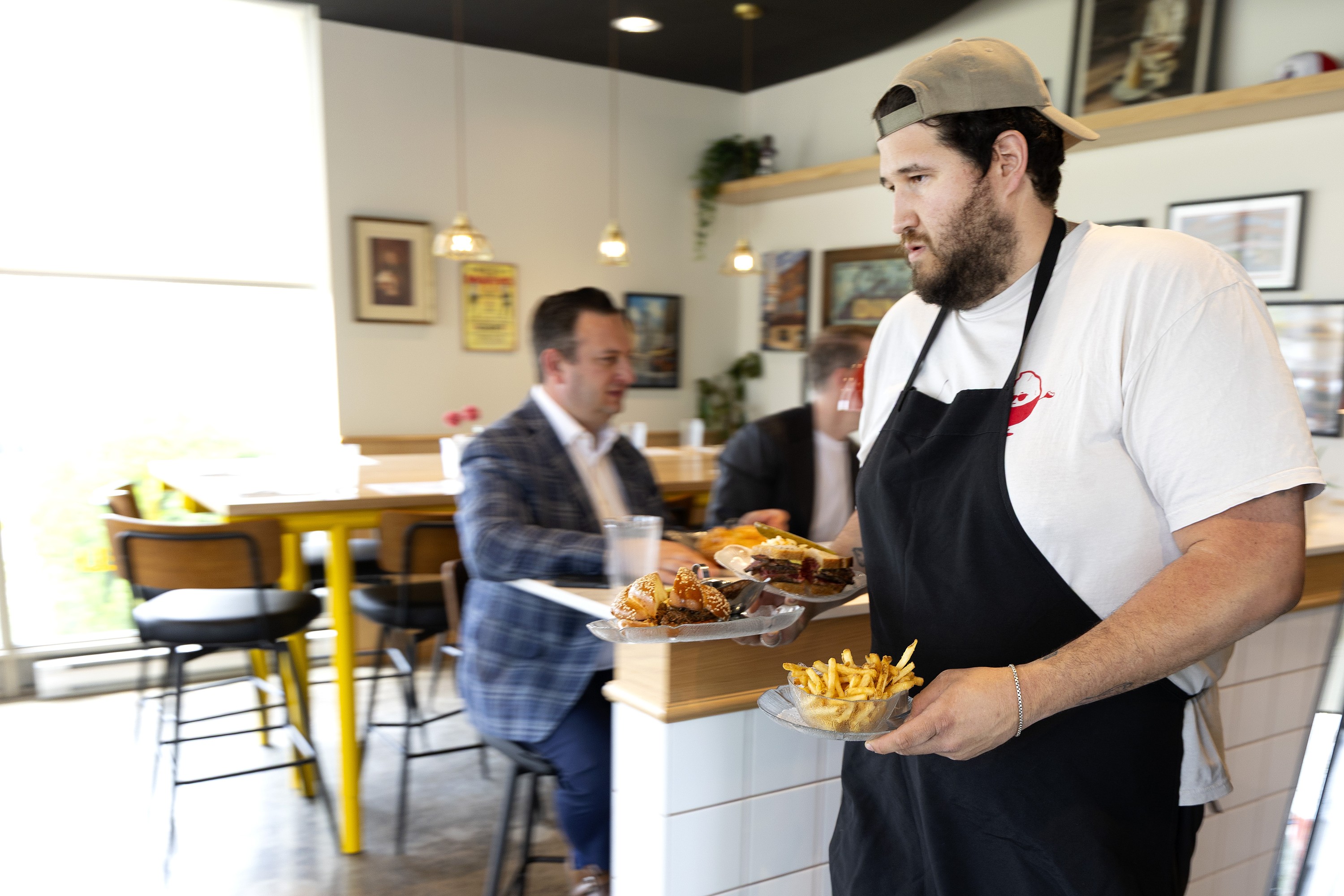 Guy carrying food to customers in restaurant.