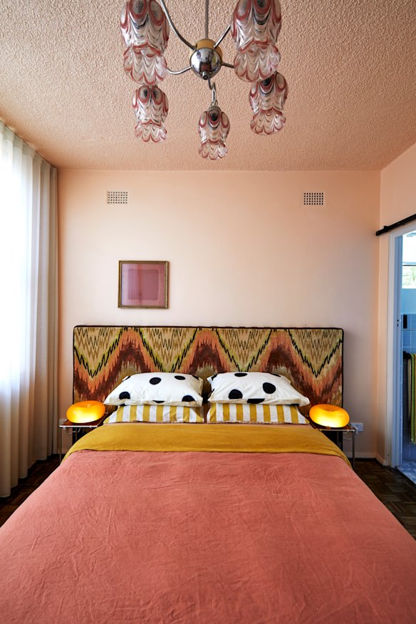 The peach-coloured bedroom features a headboard and rug designed by Ross. The overhead light is an original fitting from Etsy, the bedside lamps are from IKEA.