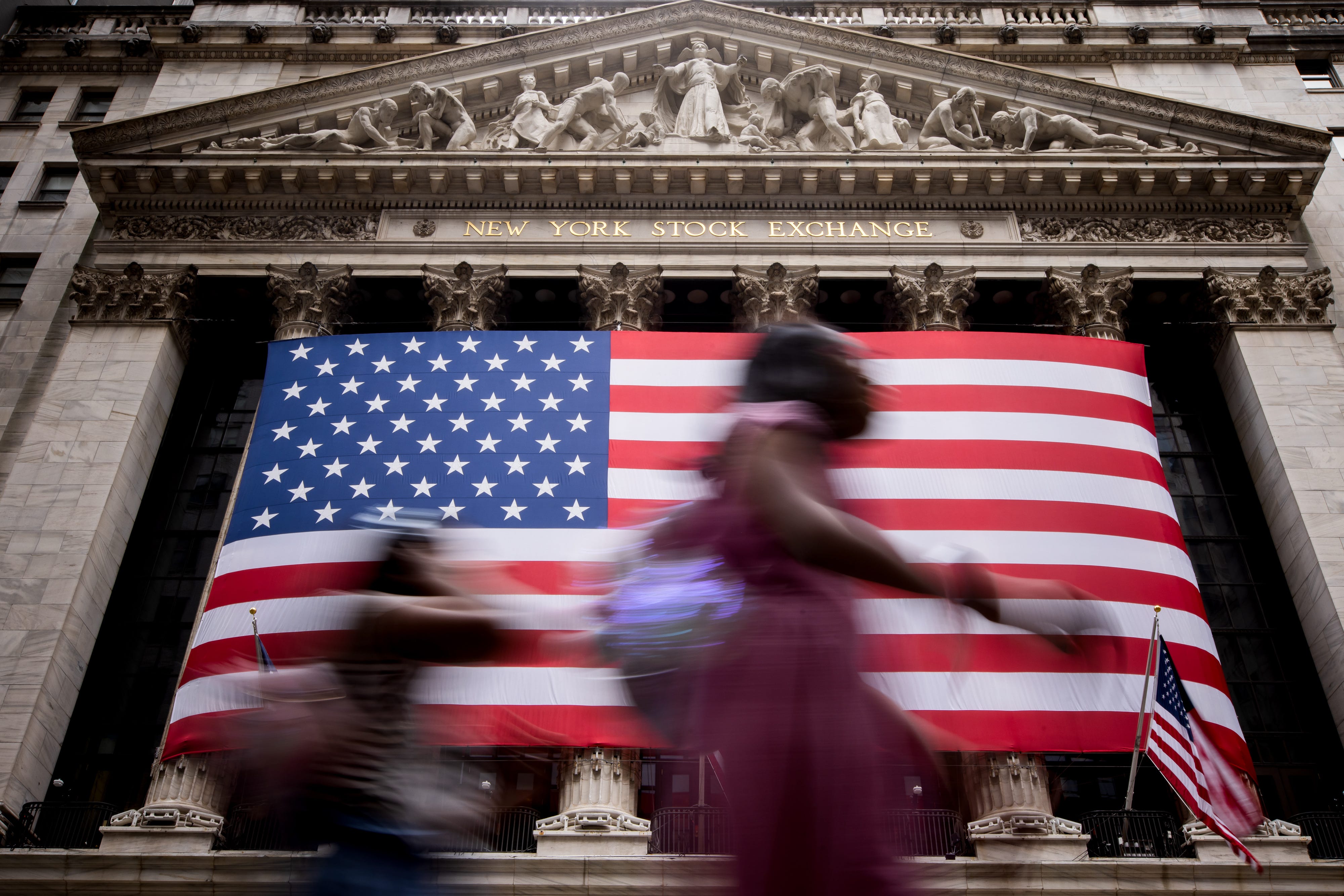 People walking past the American flag hanging at the New York Stock Exchange <a>NYSE</a>