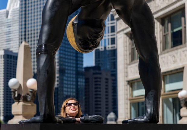 Artist Carole Feuerman looks up at her sculpture titled The Golden Mean on June 2, 2026, along North Michigan Avenue in Chicago. A series of ten swimmers in the outdoor art exhibit will line the Magnificent Mile through November. (Brian Cassella/Chicago Tribune)