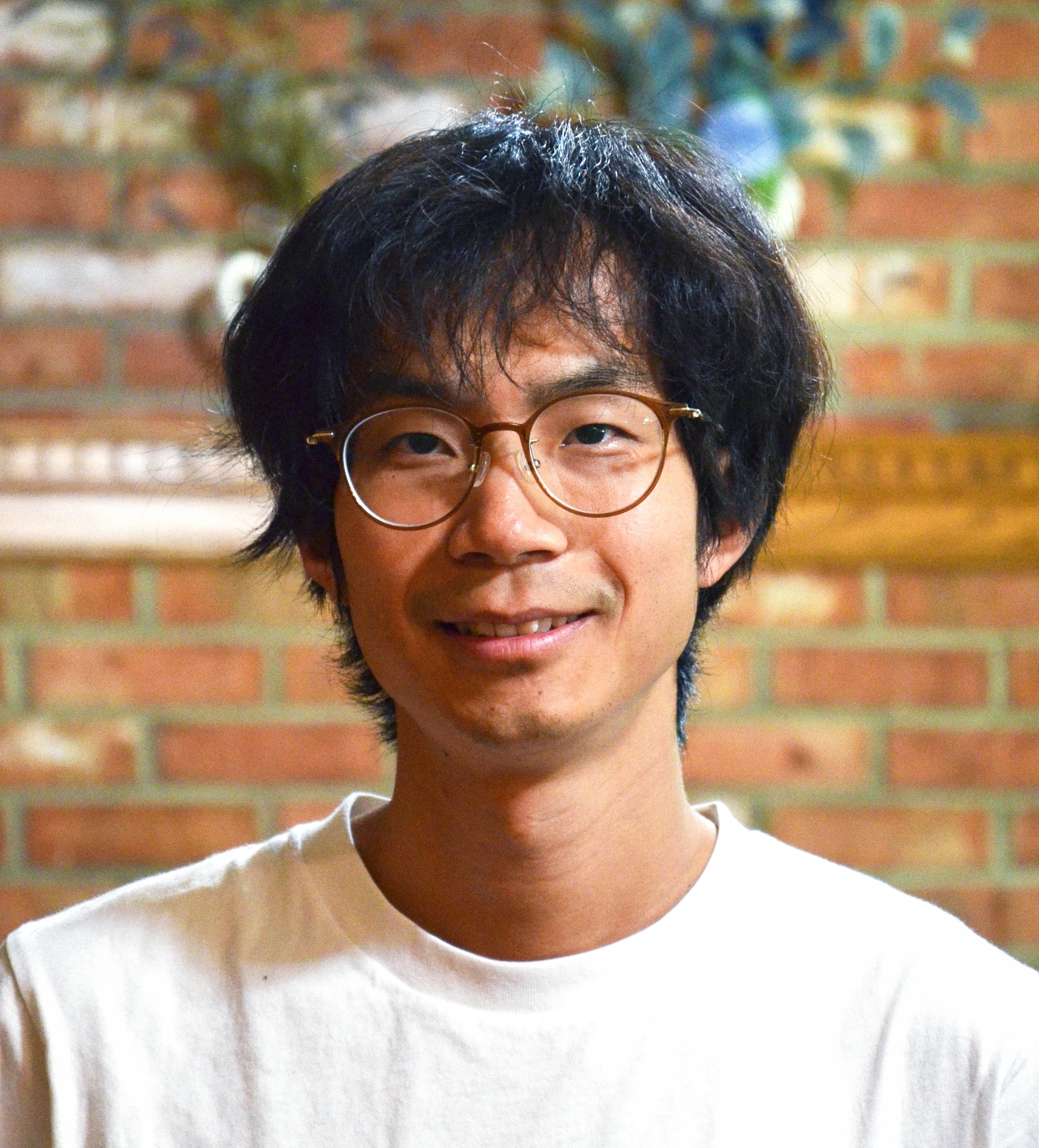 Portrait of a man in glasses in front of a brick wall