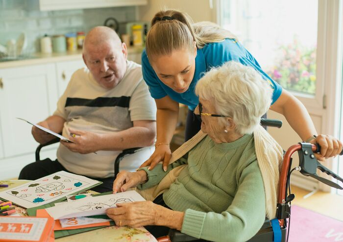 Caregiver assisting elderly woman with dementia art activities at home