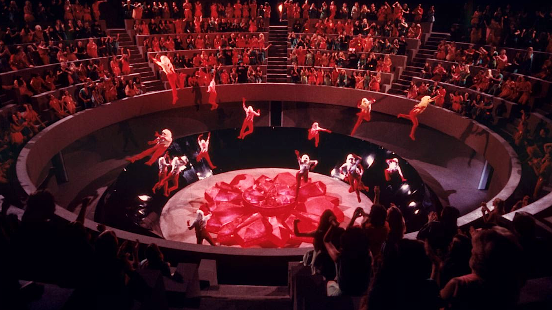 red-dressed figures rise into the air as spectators watch