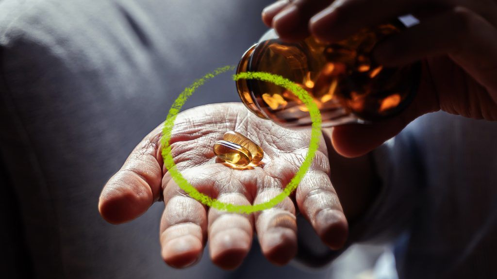A fish oil capsule in a person's hand.