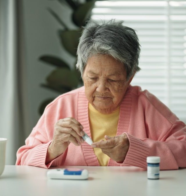 Elderly patient with diabetes using blood glucose meter. - stock photo