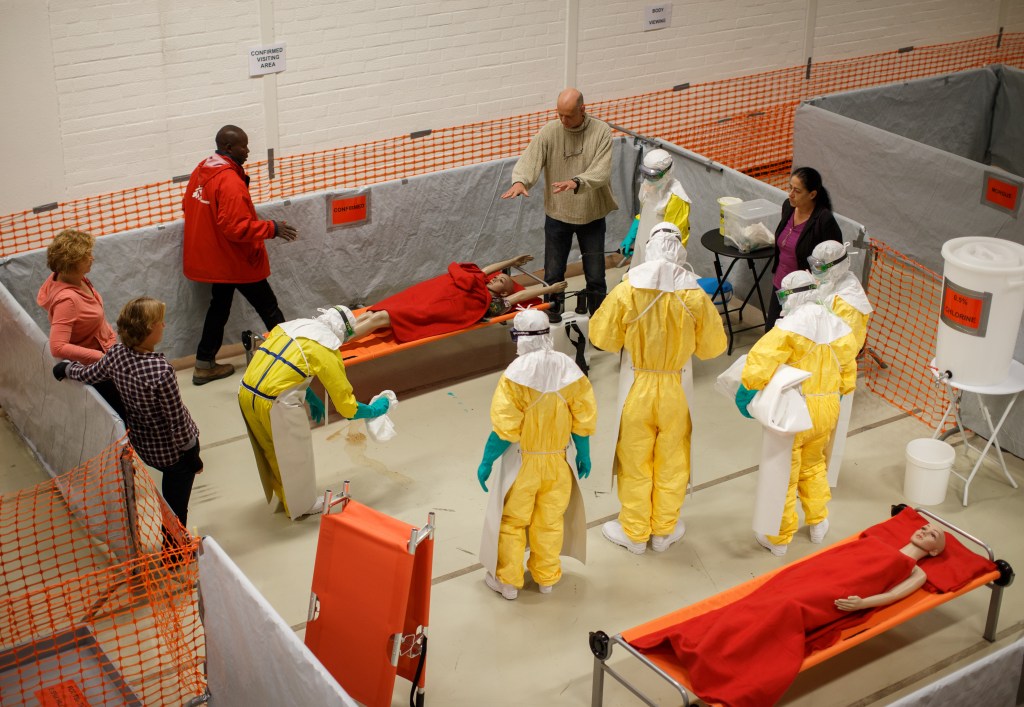 AMSTERDAM, NETHERLANDS - NOVEMBER 12:  Trainees follow the Ebola training program standing around a dummie on November 12, 2014 in Amsterdam, Netherlands. Doctors Without Borders has established a training program in a reproduction field hospital build in an old factory, without electricity and running water, in the Dutch capital for medical personnel world wide who are being sent to countries where Ebola is rife. The charity says it needs hundreds of doctors who are willing and sufficiently skilled to go to Africa to try to help combat the epidemic. The training centre in Amsterdam is the second of its kind after Brussels.  (Photo by Jasper Juinen/Getty Images)