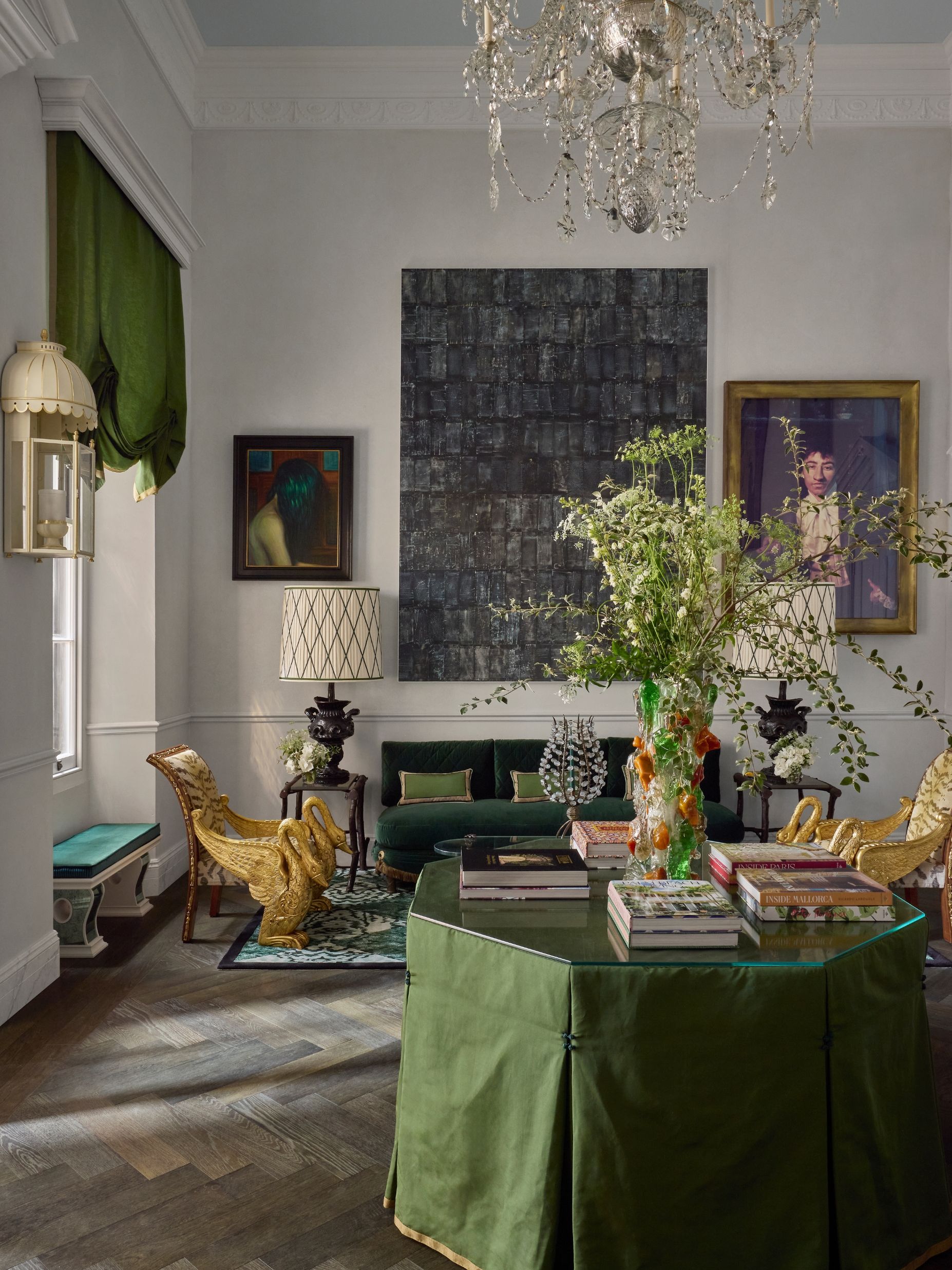an entry room with a green table, art and a dark wood floor
