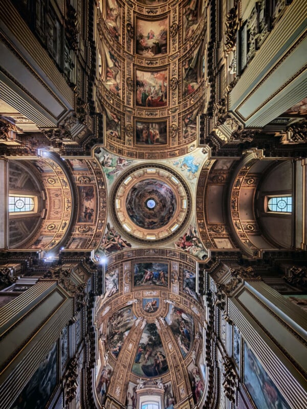 Ornate ceiling of a grand cathedral, featuring detailed frescoes, religious paintings, and a central dome with intricate artwork. Light shines through arched windows, illuminating the richly decorated architecture.
