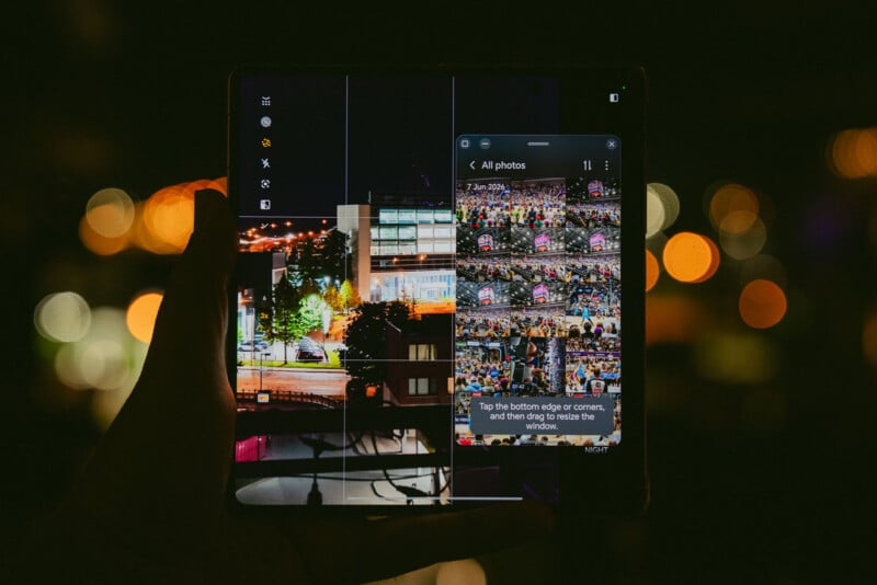 A hand holds a foldable smartphone at night, displaying a split screen with a camera view of a cityscape and a photo gallery with thumbnails of colorful crowd scenes. Blurred city lights are visible in the background.