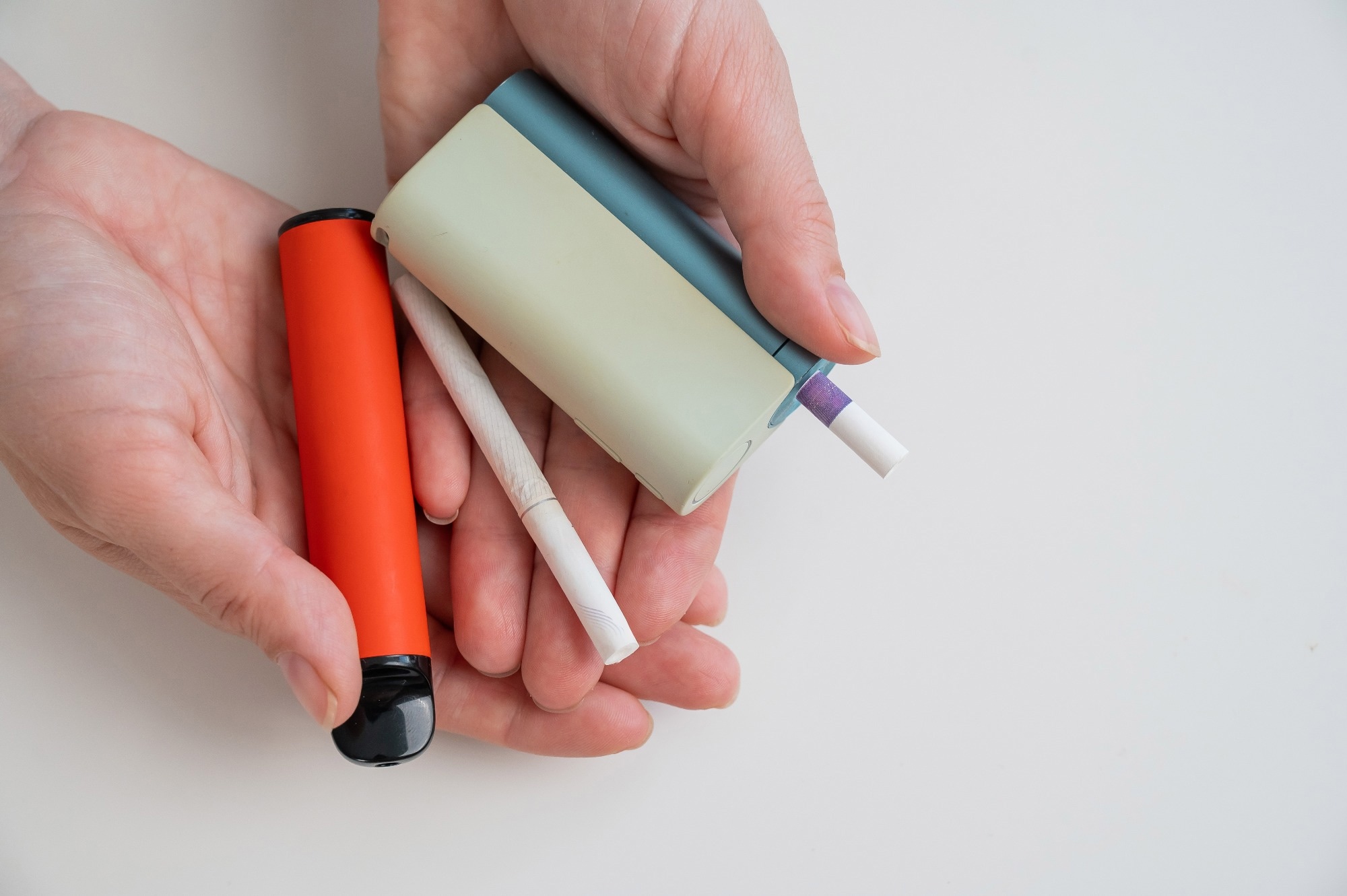 Woman holding regular, electronic cigarette and disposable vape on white background.