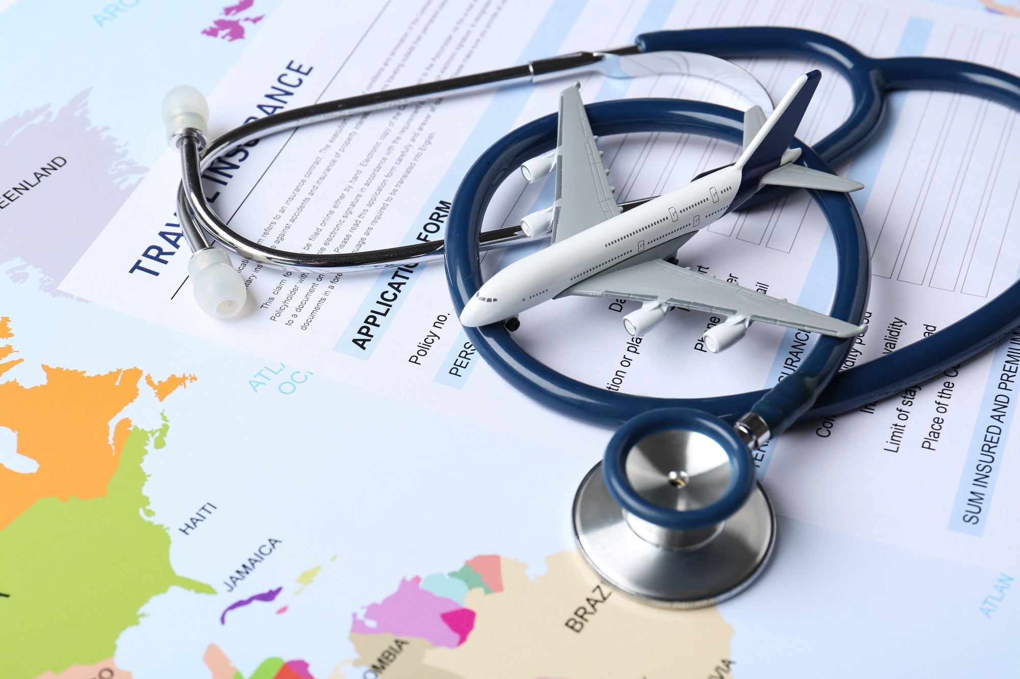 Medical tourism. Travel insurance application form, stethoscope and airplane model on world map, closeup