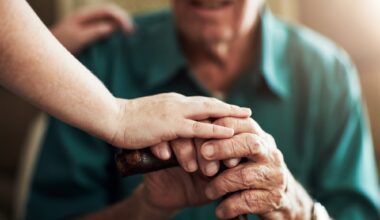 Hands, elderly man and woman in nursing home with support for retirement, assisted living and alzheimer care. Female caregiver, senior patient and touch with kindness for trust, healthcare and help