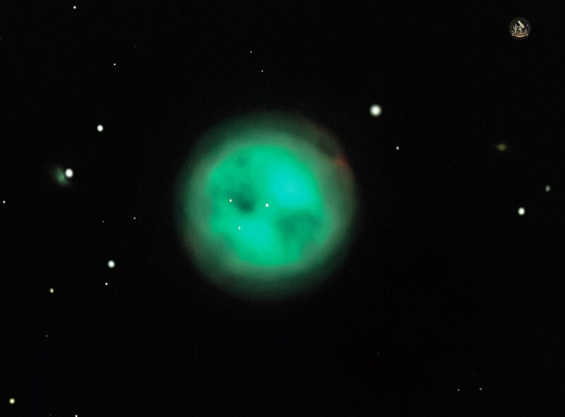 A large sphere of electric green gas with 3 large darks spots, surrounded by sparse stars.