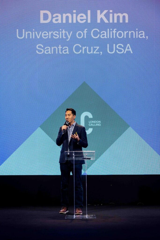 Daniel Kim speaks into a microphone on a stage