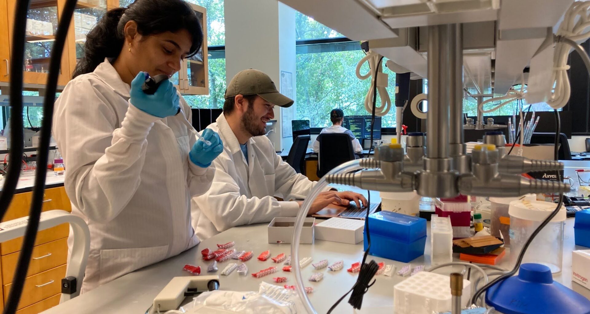 Two people in white lab coats work in the lab