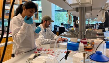 Two people in white lab coats work in the lab