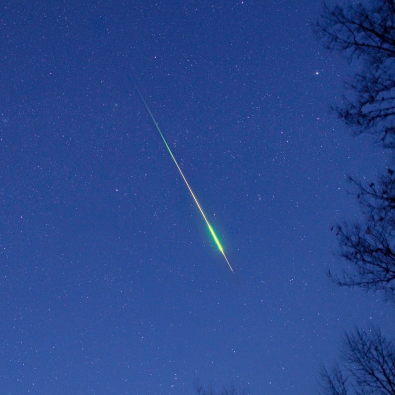 Asteroid or comet: A view of the sky with a bright greenish streak that is fatter near the bottom.