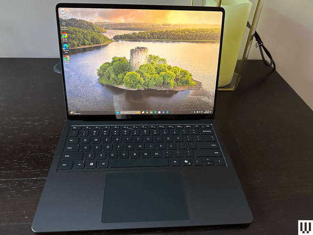 Front view of a laptop sitting on a wooden desk with the image of an island on the screen