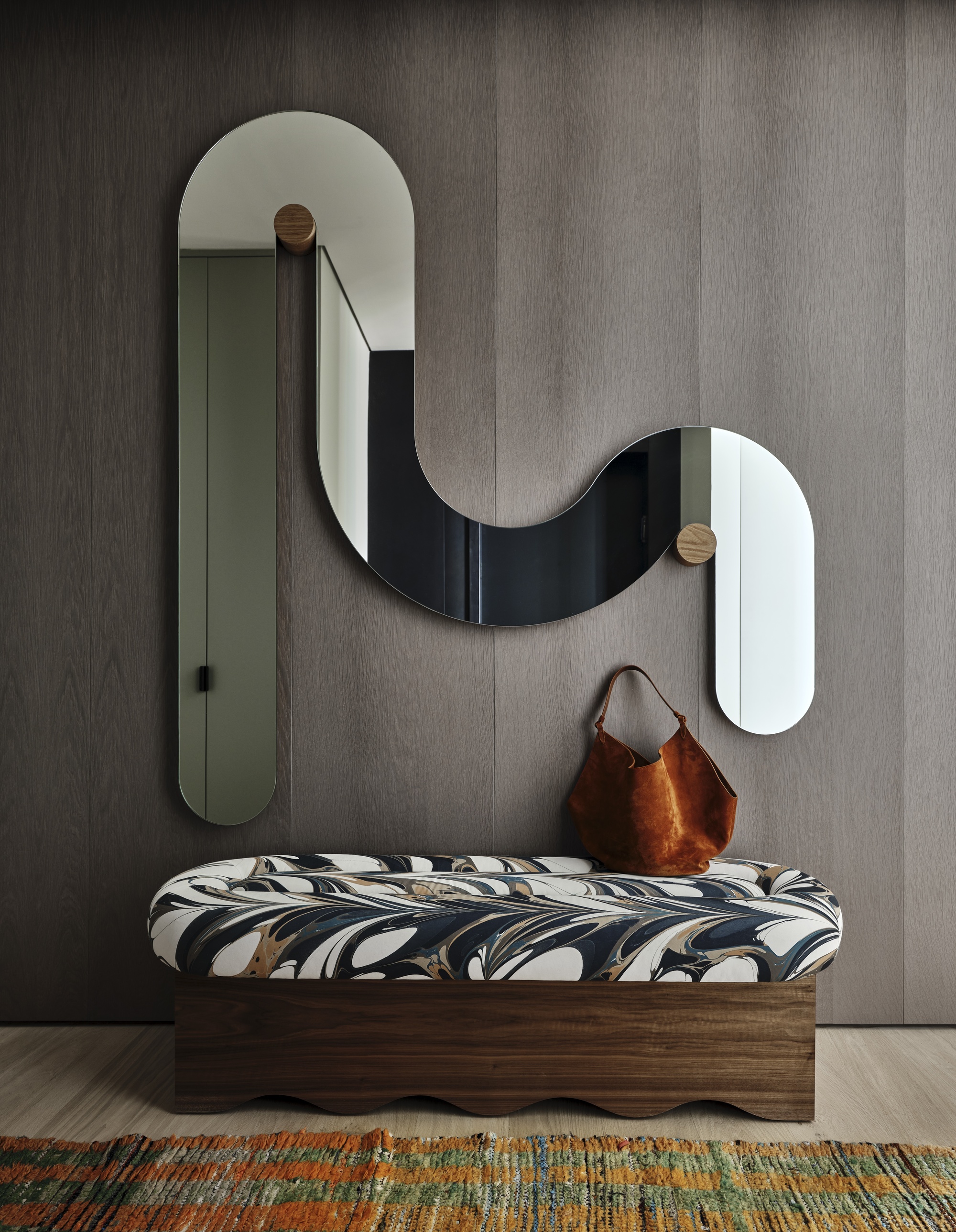 hallway bench with marbled pattern fabric, timber floors, colorful woven rug, squiggle mirror