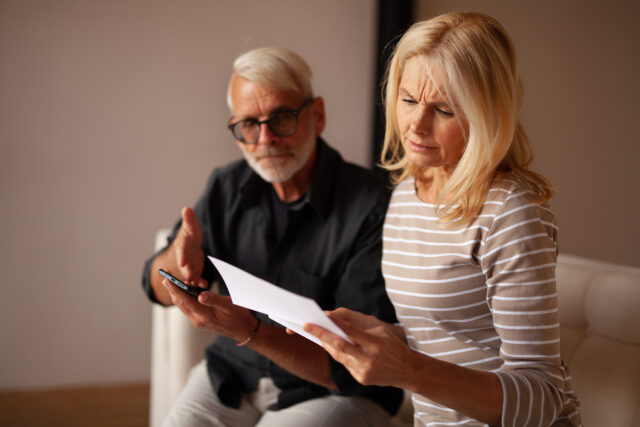 Older couple looking concerned at a document and cellphone