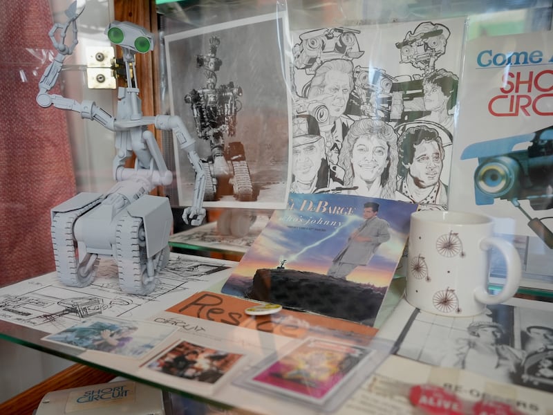 collection of items from the movie Short Circuit including a model robot, a record from the movie's title track and various photos
