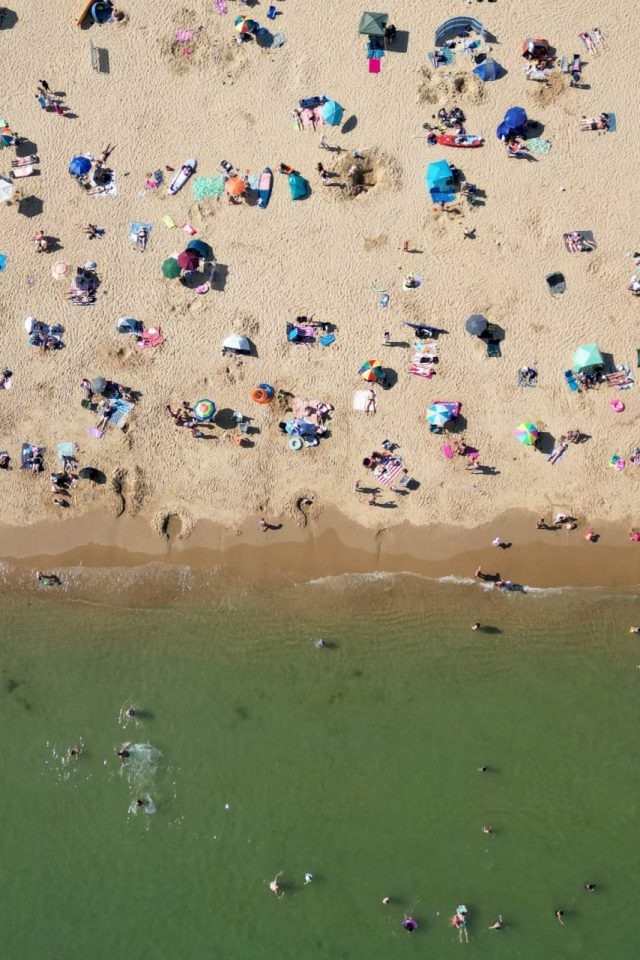 TOPSHOT - An aerial picture shows people playing in the sea and relaxing in the sunshine on Bournemouth beach on the south coast of England on May 26, 2026, as heatwave conditions spread to parts of southeast England and London. Britain registered on Tuesday its hottest-ever May temperature on record, with the mercury rising to 35C near the capital. (Photo by JUSTIN TALLIS / AFP via Getty Images)