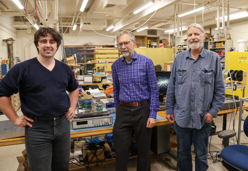 Project team standing in lab in front of electronics work bench