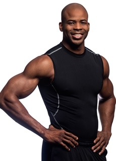man facing the camera from hip height holding his hips and smiling wearing a black vest