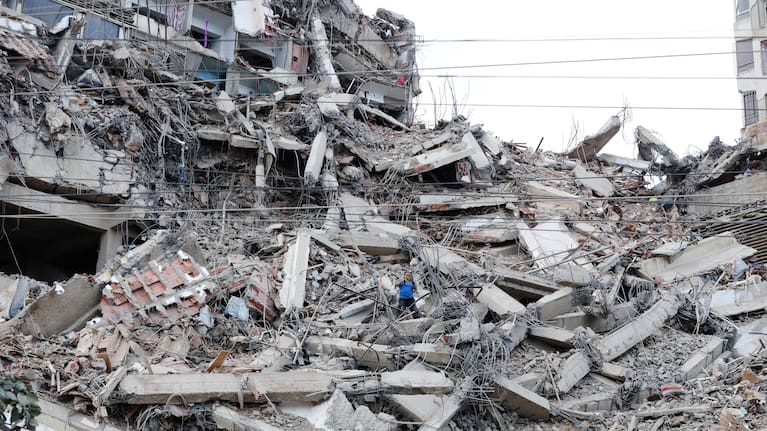 A man walks among the rubble of a building that collapsed in earthquakes the previous day in La Guaira, Venezuela