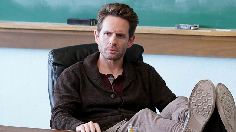 Jack with his feet propped up on a desk, frowning