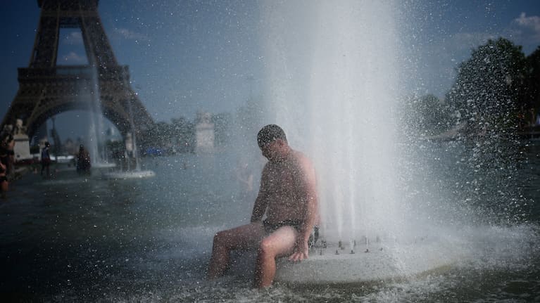 A person cools off at Trocadero fountain near the Eiffel Tower during a heat wave in Paris.