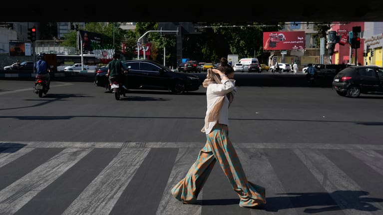 A woman adjusts her headscarf as she crosses an intersection in northern Tehran, Wednesday, June 10, 2026. 