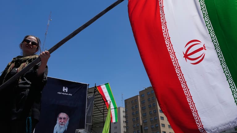 A woman waves an Iranian flag during a pro-government campaign as a portrait of the slain Supreme Leader Ayatollah Ali Khamenei.