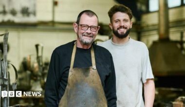 Brian Fell (L) has short cropped brown hair, brown glasses and wears a black sweat shirt and stained khaki apron while George Fell (R) has brown hair and beard and wears a  grey T-shirt.