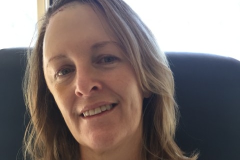 A woman with brown hair, smiling, with a scar visible across her forehead.
