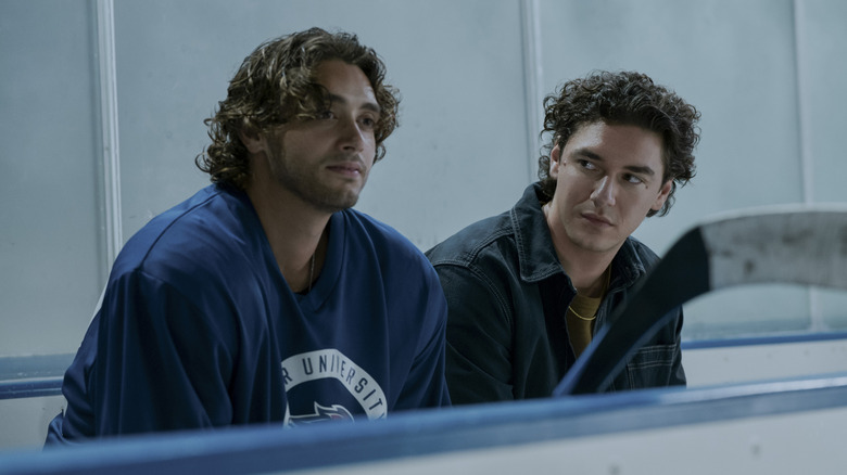 John Logan (Antonio Cipriano) in blue Briar U jersey and Garrett Graham (Belmont Cameli) in casual clothing sitting on hockey bench