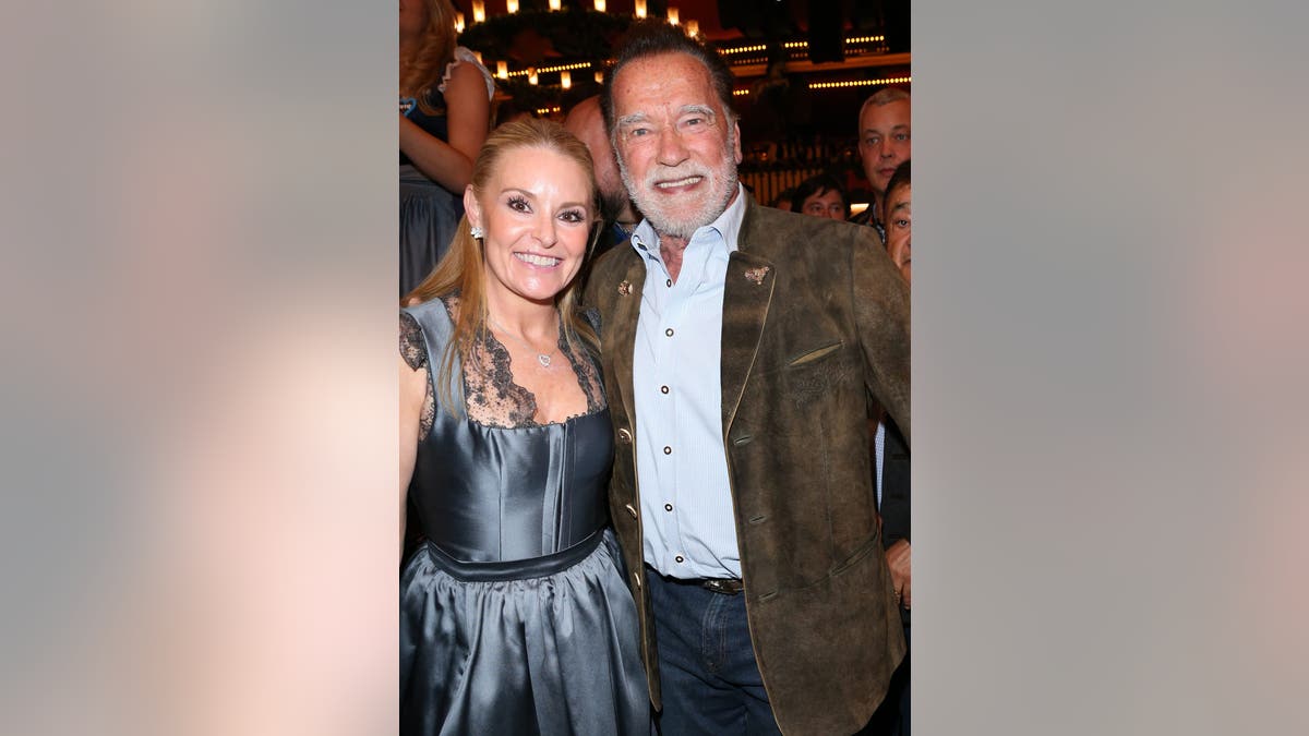 Arnold Schwarzenegger and Heather Milligan standing together at Oktoberfest in Munich