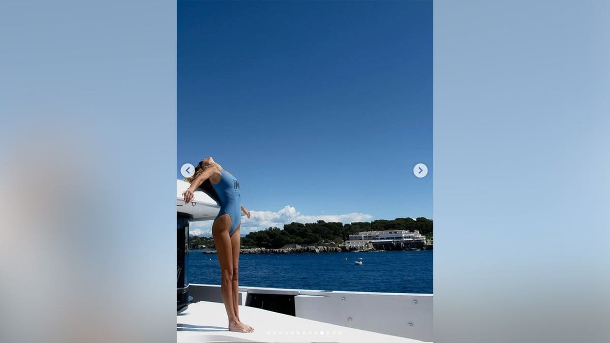 Bella Hadid standing with her head tilted back on a yacht in 2026.