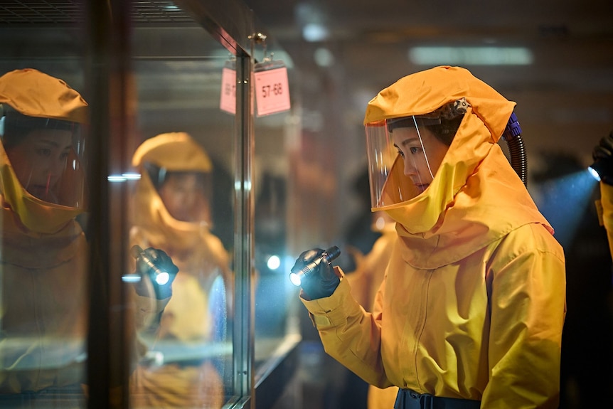 A person in PPE looks into a glass case.