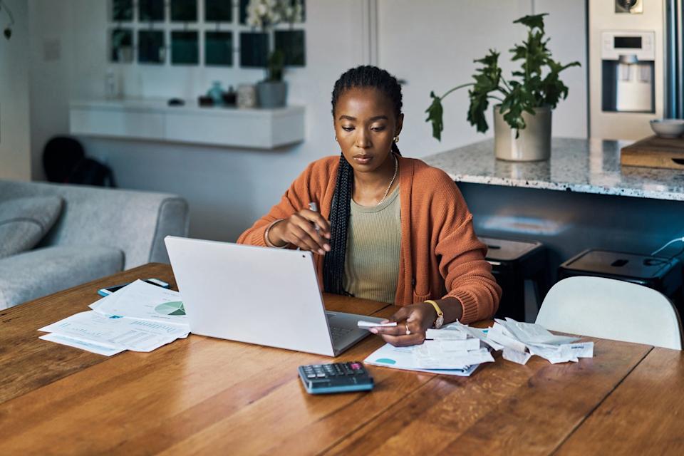 Analyst working with a laptop and calculator in a home office.