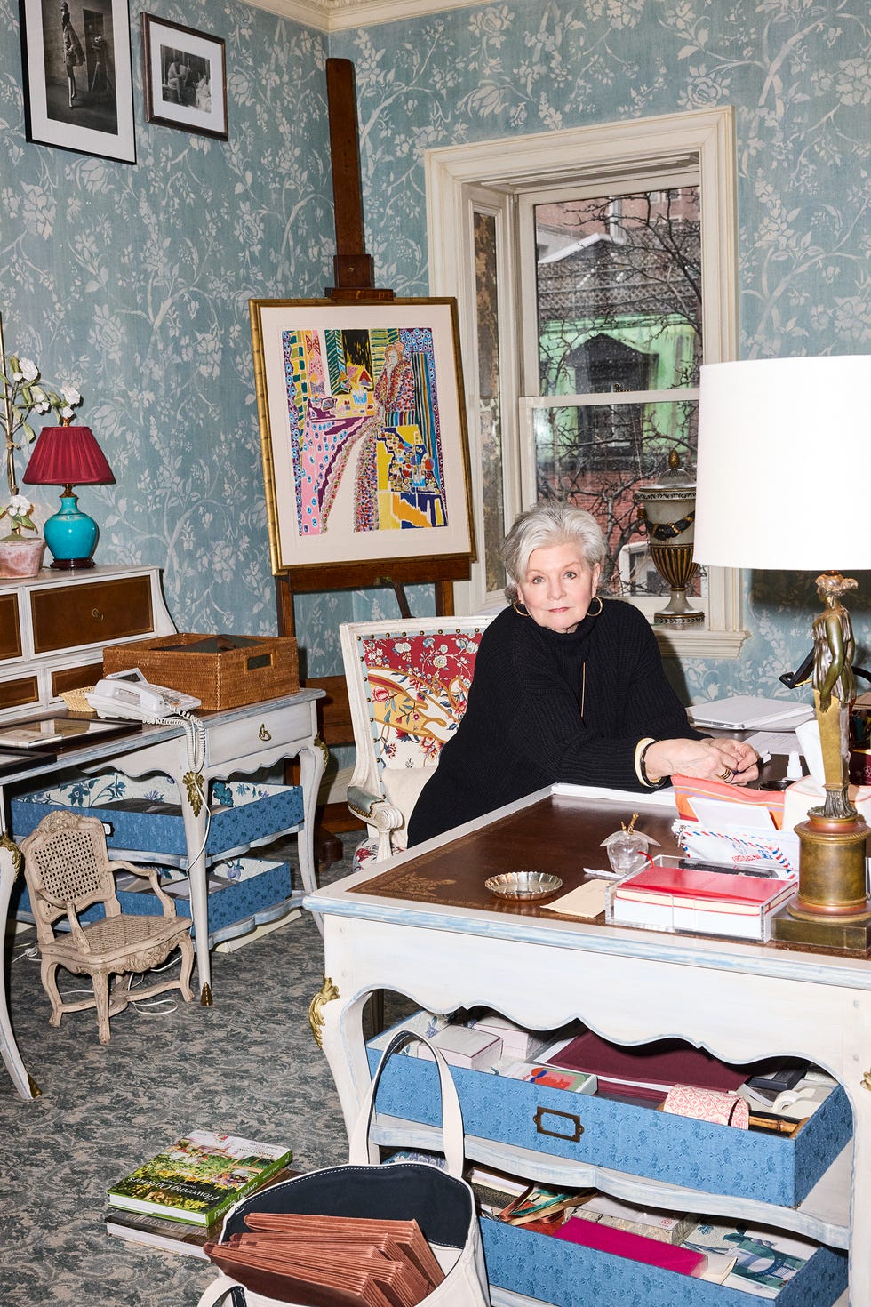 Woman sitting at a desk in an artfully decorated room with vibrant painting.