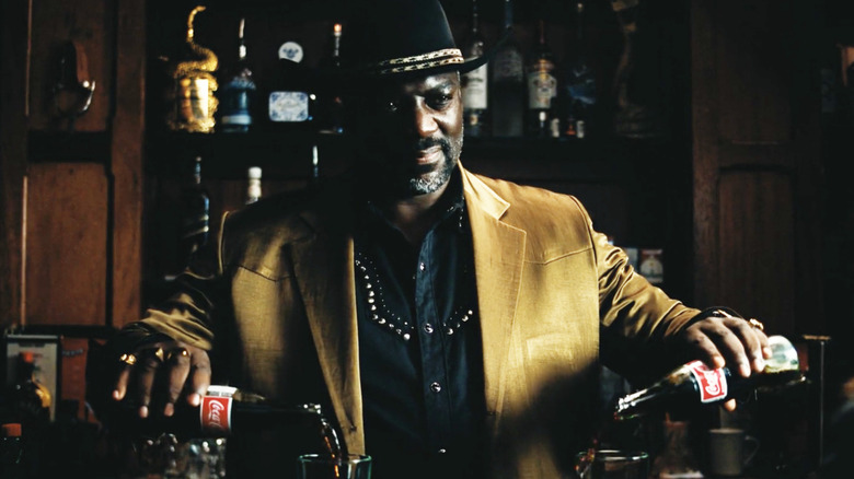 Alamo Brown smirking while pouring two Coca-Colas