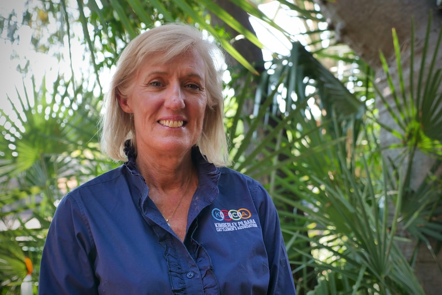 woman in KPCA-branded shirt stands in front of tree smiling at camera