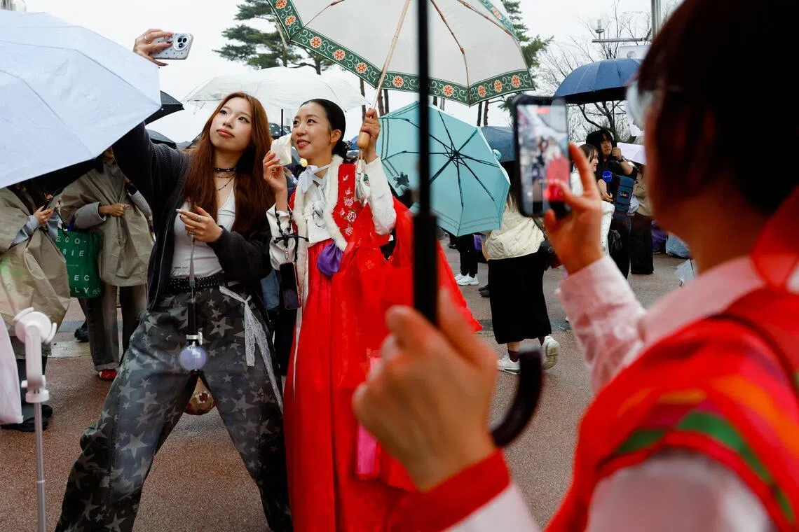 A BTS fan wearing Korean traditional clothing Hanbok, takes a selfie ahead of the band's concert in Goyang, on April 9.
