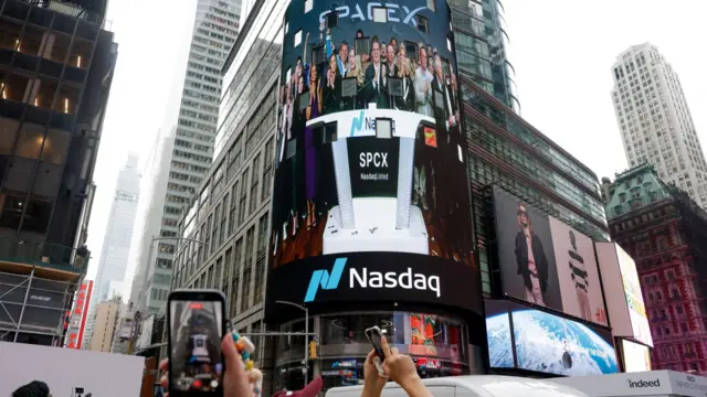 People gather to watch a live feed with SpaceX CEO Elon Musk on the day of SpaceX's initial public offering (IPO) at the Nasdaq MarketSite, in New York City, U.S., June 12, 2026.