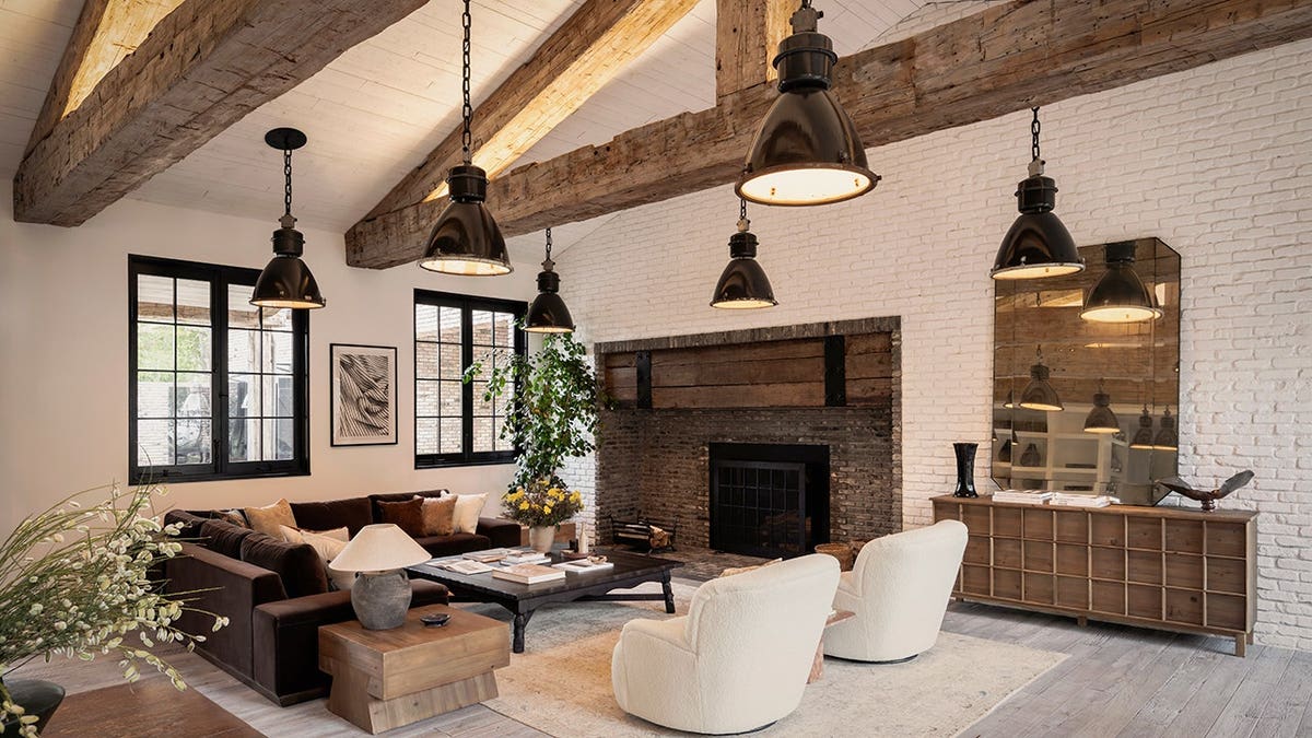 A living room with a brick fireplace and exposed beams on the ceiling.