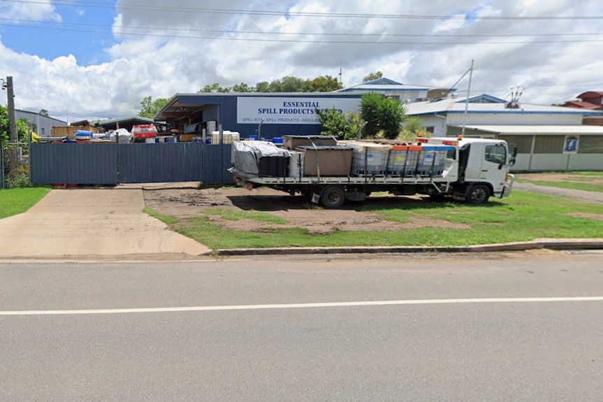 Roadway, grass driveway, high fence, loaded truck, signage, stored gear