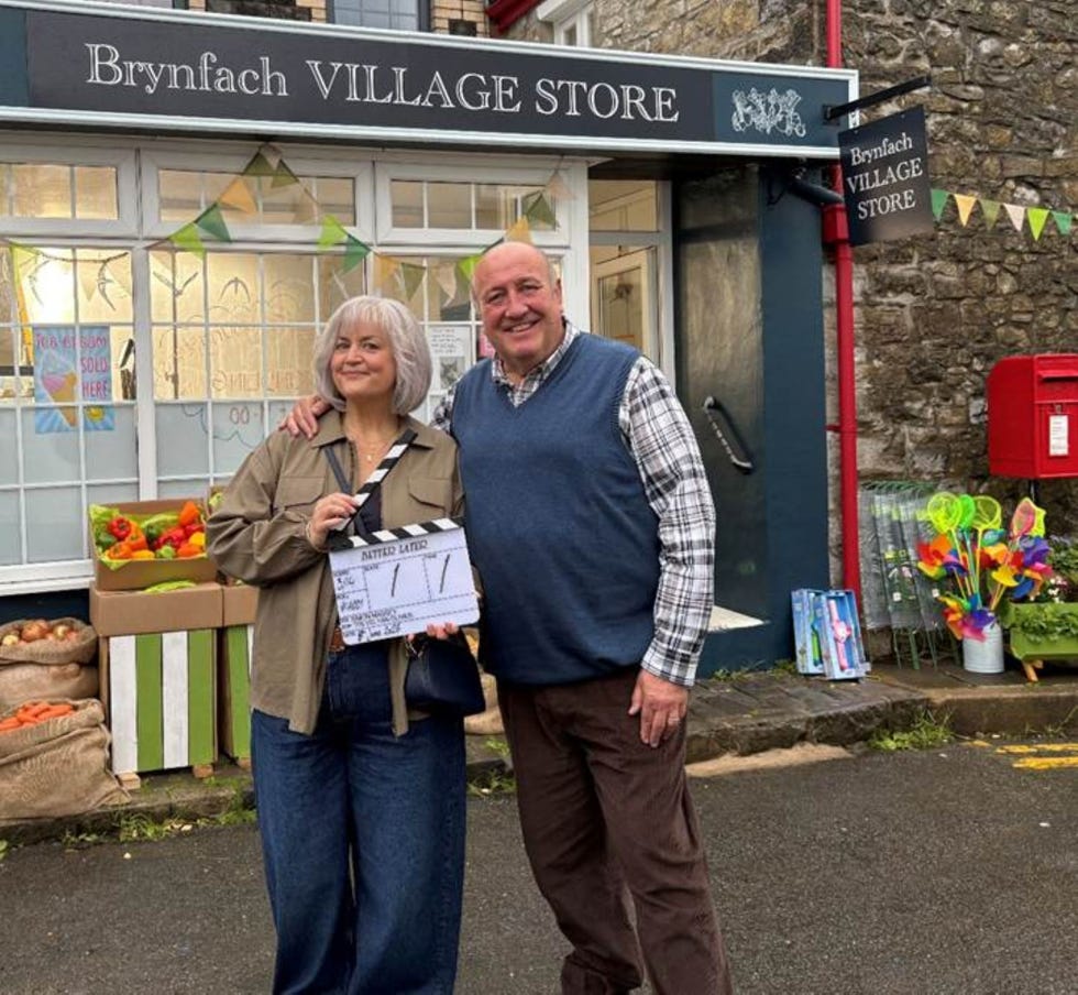 better later filming ruth jones steve speirs two individuals posing outside a village store holding a clapperboard